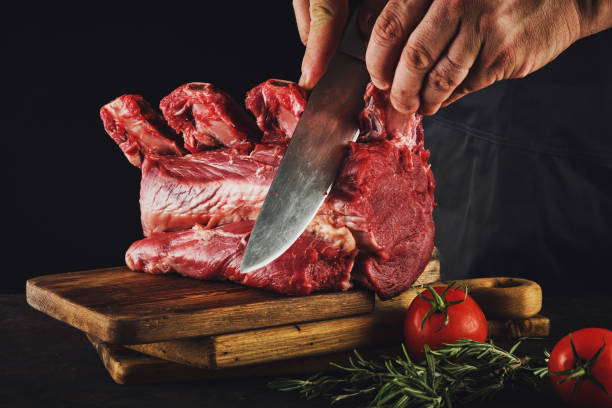istock Male butcher cuts raw beef meat. 1188464753