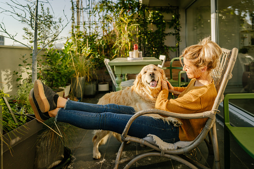 Photo of young woman and her pet enjoying together on the balcony of their loft apartment