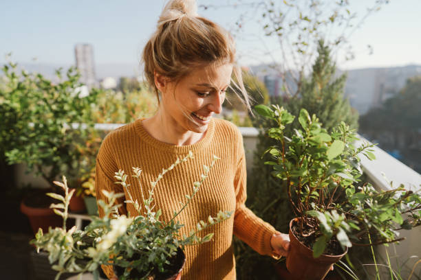 Taking care of my plants Photo of young woman taking care of her plants on a rooftop garden moment of silence stock pictures, royalty-free photos & images