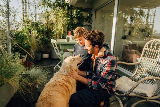 Relaxing moments with our dog Photo of father, son and their pet enjoying together on the balcony of their loft apartment apartment balcony garden stock pictures, royalty-free photos & images