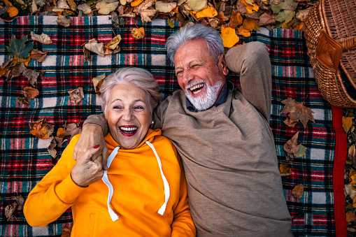 Funny picnic. Hilarious laughing senior couple lying on plaid blanket and having fun during picnic.