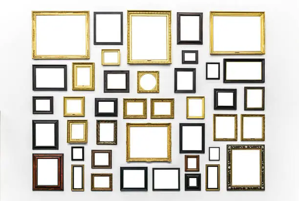 Photo of Plenty of white clipped paintings frame hanging on a white wall. Copy or empty space for mockups or templates. Museum Art exhibition.