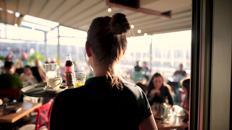 Young waitress serving drinks at beautiful rooftop cafe during sunny day