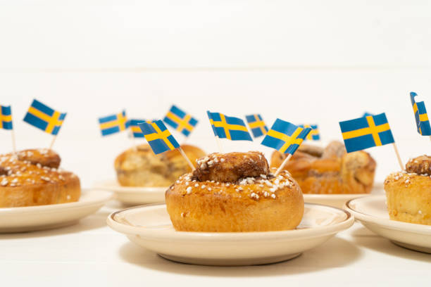 istock Swedish cinnamon buns (kanelbullar) on the white wooden table. Swedish flags. Coffee break (fika) 1188478936