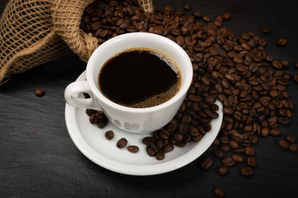 taza de café caliente y granos de café en vista superior de fondo negro - coffee black coffee cup coffee bean fotografías e imágenes de stock