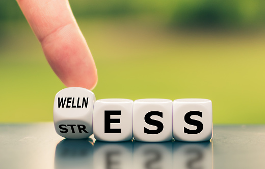 Wellness instead of stress. Hand turns a dice and changes the word 