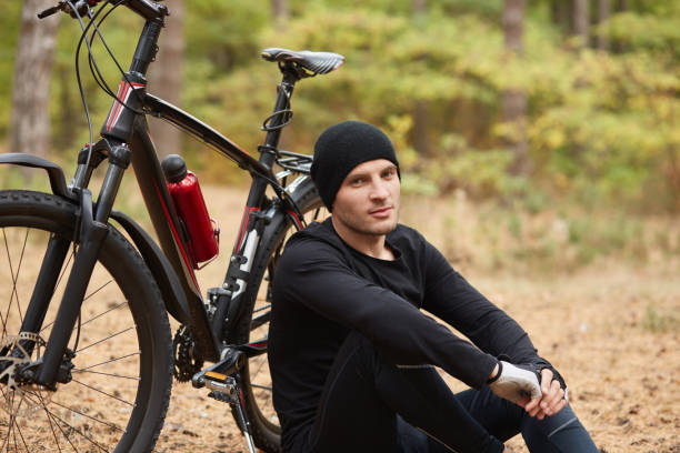 istock Image of confident handsome model posing over bicycle background, relaxing and enjoying free time, being in for sport, breathing fresh air, looking directly at camera, having rest around nature. 1188480623