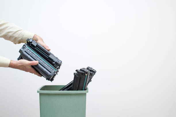 Male hands of an office worker stack spent cartridges in a bucket against a white wall. Male hands of an office worker stack spent cartridges in a bucket against a white wall. The concept of the problem of disposal of harmful chemical waste of office equipment. cartridge stock pictures, royalty-free photos & images