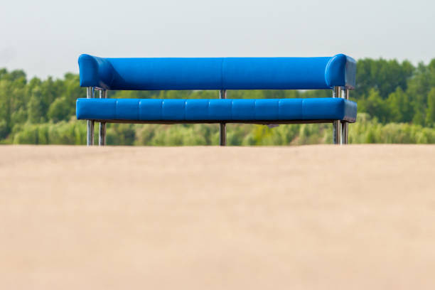 A blue simple bench at a sightseeing spot in Japan.\nTwo women walking in the distance.\nEnoshima, Fujisawa City, Kanagawa Prefecture.