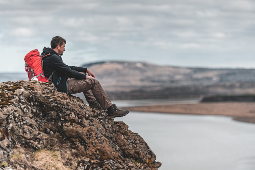 A man with a red backpack admires the landscape in Þjórsárdalsvegur in the southern region of Iceland.