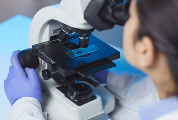 istock Over shoulder view of unrecognizable scientist investigating sample on glass slide via microscope in laboratory 1188486183