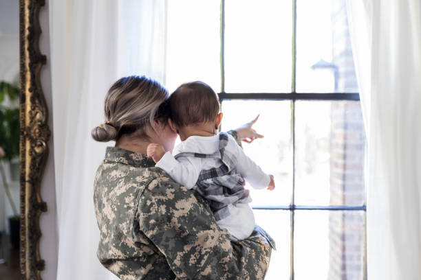 istock Soldier mom shows daughter something through window. 1188487380