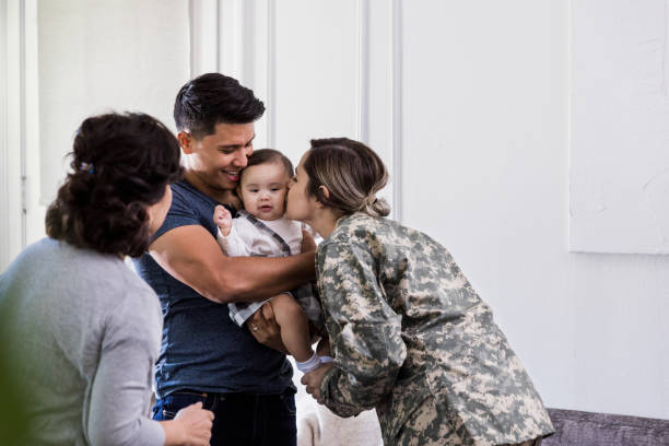 o soldado fêmea beija a filha nova em cima de seu retorno para casa - grandmother senior adult child baby - fotografias e filmes do acervo
