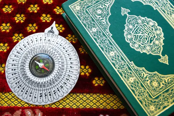 White compass, beautiful Arabian ornament carpet and Koran needed for Muslim prayer