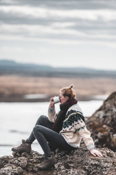 Girl sits on a rock and savor hot tea