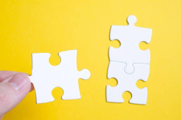istock The concept of finding a solution to a problem. A piece of the puzzle is held by a man with his fingers next to others on a yellow background. 1188502058