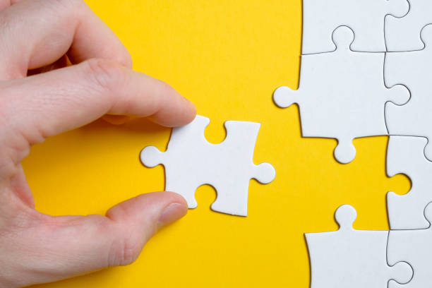 istock The concept of finding a solution to a problem. A piece of the puzzle is held by a man with his fingers next to others on a yellow background. Flat lay. 1188502182
