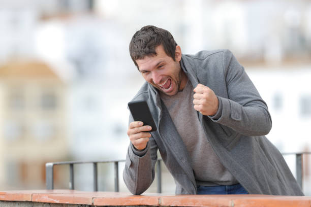 istock Excited man checking phone in winter in a balcony 1188506801
