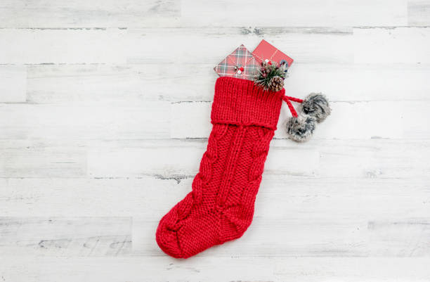Red knitted Christmas stocking on white wooden background with space for copy stock photo