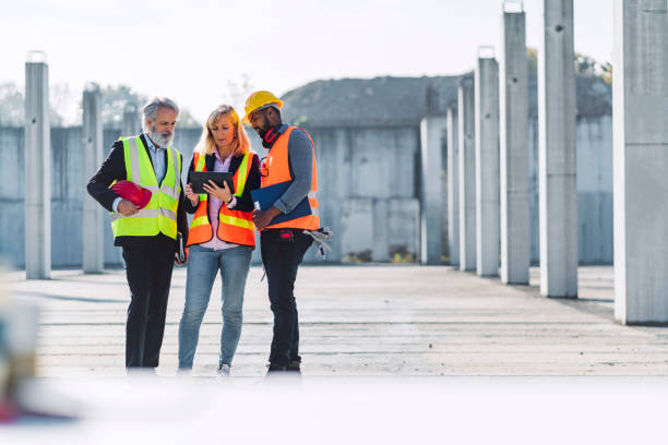 istock Small group of thee diverse people in reflective vests working on construction site 1188510401