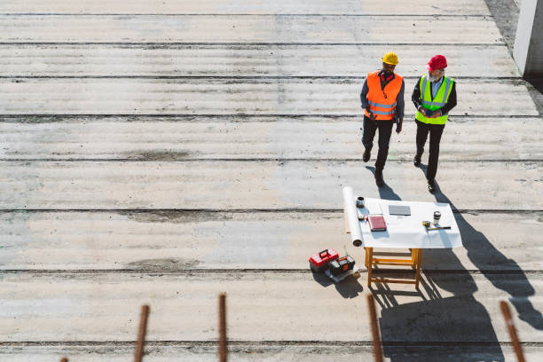 istock A couple of engineers on empty construction site and a desk covered with blueprints 1188510425