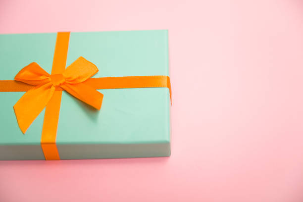 istock green box with gifts with an orange bow on a pink 1188511586