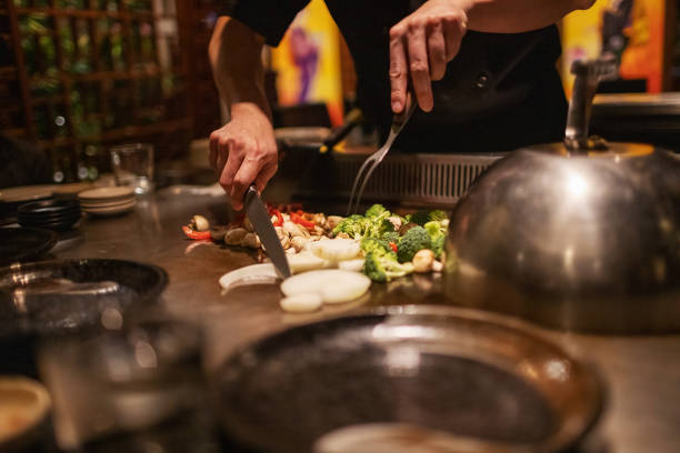 teppanyaki chef cooking and cutting up vegetables - teppan yaki imagens e fotografias de stock