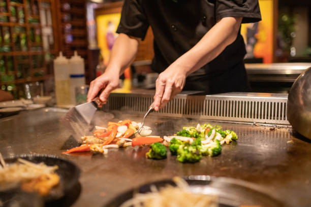 chef teppanyaki cocinando y cortando vegetales - teppan yaki fotografías e imágenes de stock