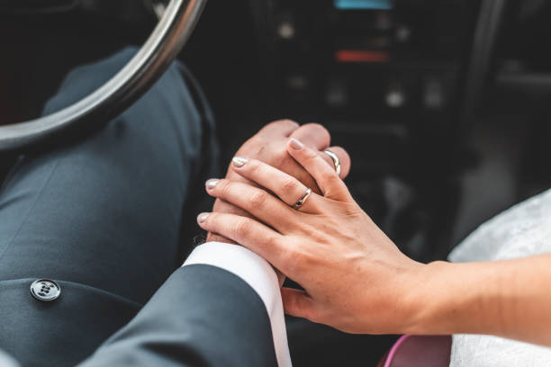 Rear view of a married couple holding hands while sitting in their car together. Man and woman on a road trip.