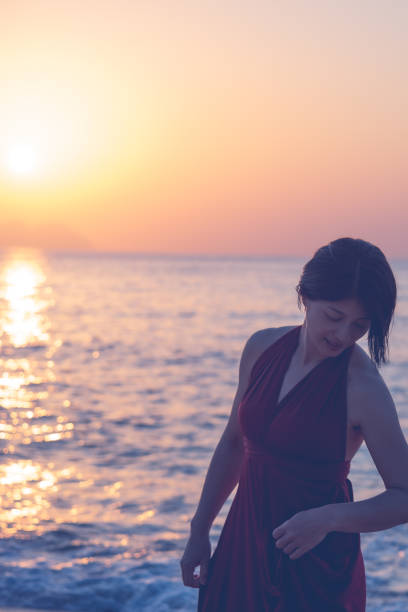 istock woman in red dress on the sunset beach 1188517543
