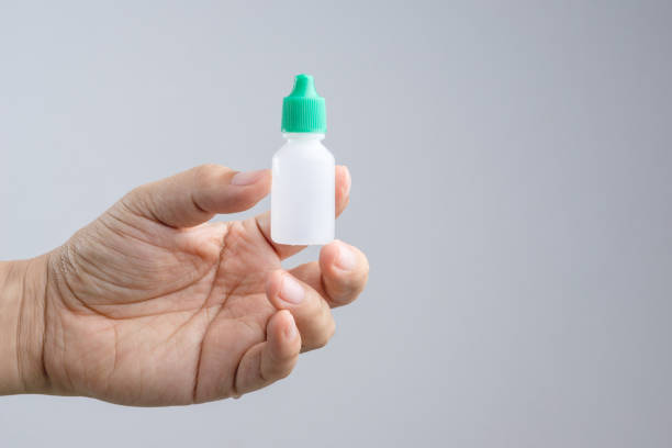 Hand holding eye or ear drop bottle on white background