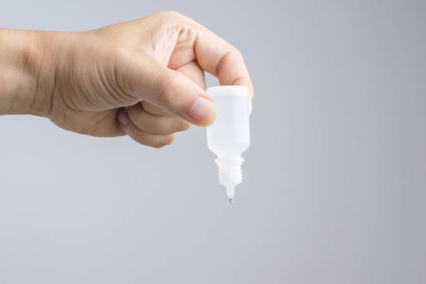 Hand holding eye or ear drop bottle on white background
