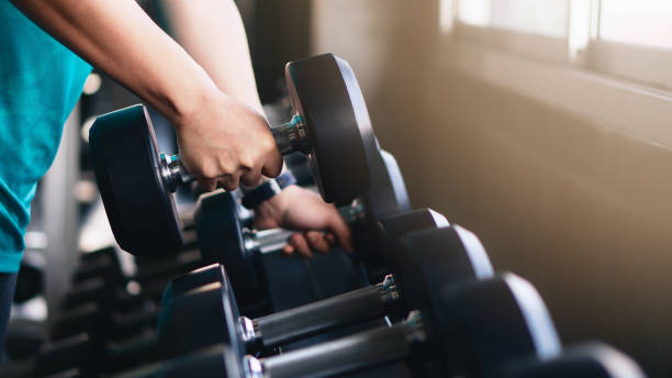 hands of man lifting dumbbells on rack in gym or fitness stock photo