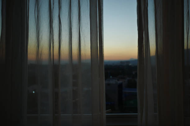 istock sunlight through white curtain with sunset sky view outside the window 1188527587