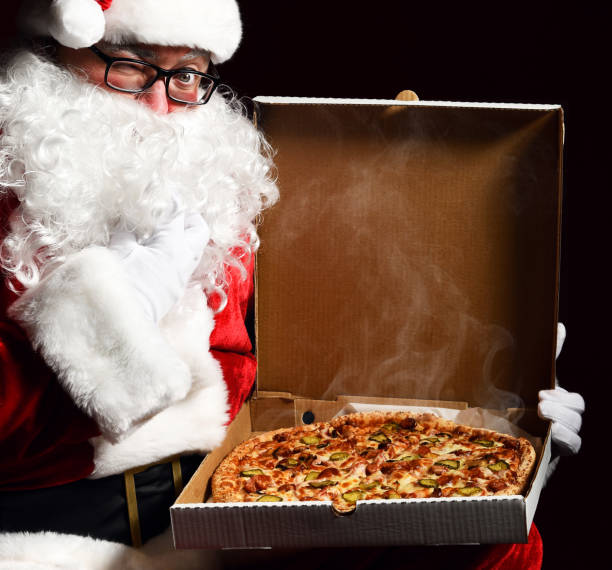 Happy Santa Claus hold big hot steaming pizza offering with copy space. New year and Xmas fast food stock photo