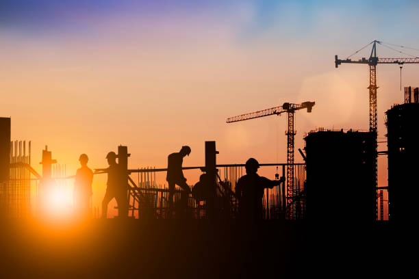 ライトフェアで業界の背景をぼやけた背景の上に現場で働くエンジニアと建設チームのシルエット。複数の参照イメージから一緒に作成する - housing project business team teamwork ストックフォトと画像
