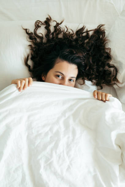 istock woman having fun in bed hiding after blanket 1188554596
