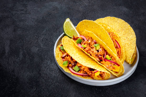 istock Cochinita pibil taco shells, a Mexican snack with pulled pork, avocado and marinated red onion, a close-up shot on a dark background with a place for text 1188555966