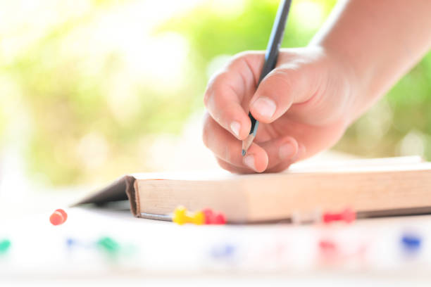 istock A close up of a hand writing a book with a pencil 1188561297