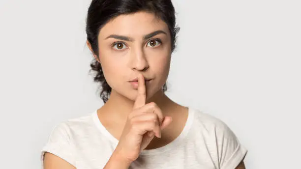 Photo of Headshot portrait serious Indian woman showing hush gesture close up