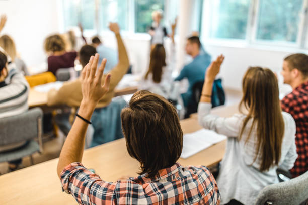 istock Back view of college student raising his hand on a class at lecture hall. 1188564404