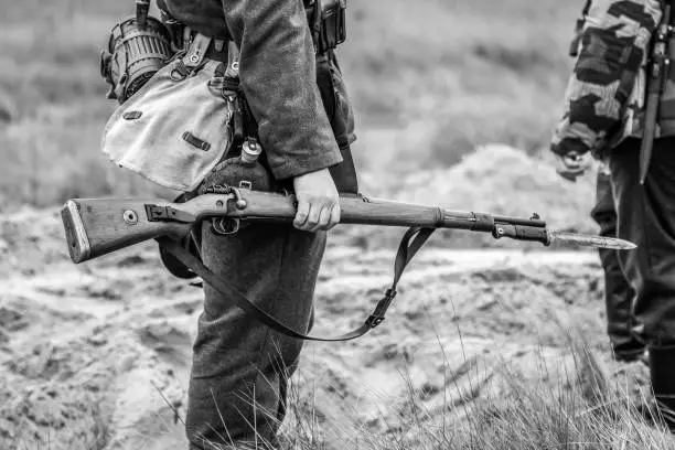 A rifle with a bayonet with a knife in the hands of a Wehrmacht soldier from World War II. Black and white photography