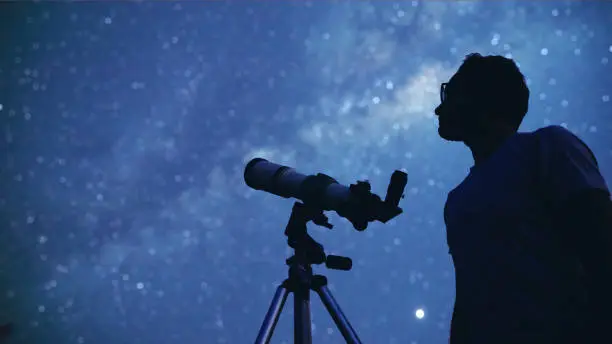 Photo of Astronomer with a telescope watching at the stars and Moon. My astronomy work.