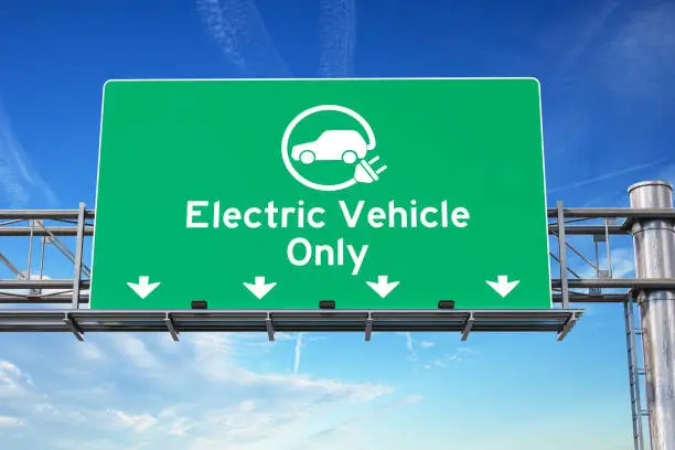 Photo of Electric vehicle only green traffic road sign with symbol of electric car on sky background. Ecology and environmental concept background.