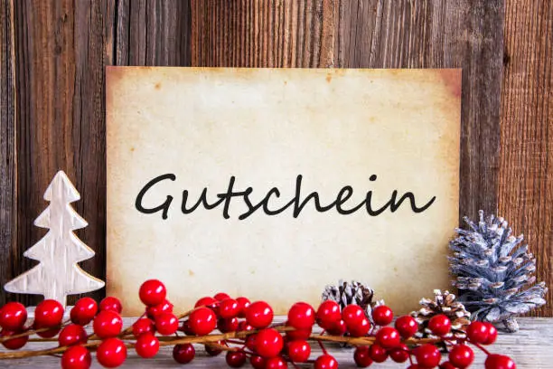 Paper With German Text Gutschein Means Voucher. Christmas Decoration And Wooden Background