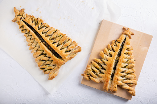 Puff pastry pie with cheese and spinach in shape of  Christmas tree  on white background. Top view. Copy space.