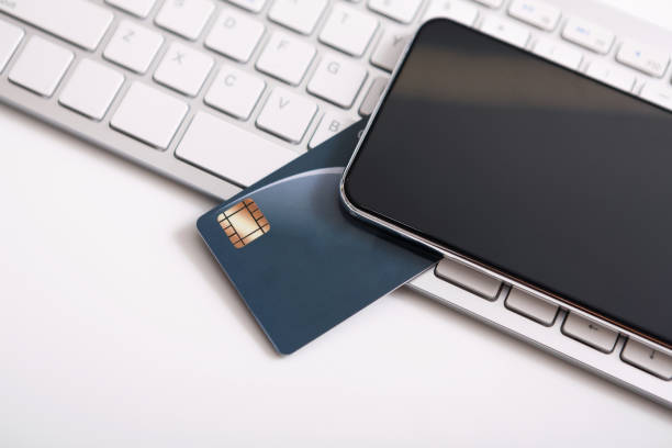 istock Smartphone with black screen and credit card on laptop keyboard 1188575913