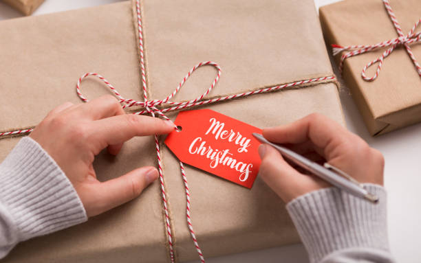 istock Woman writing Merry Christmas text on red label 1188576681
