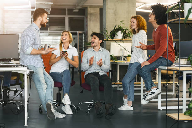 Young coworkers having pleasant talk in office Informal corporate meeting. Young coworkers having pleasant talk in office office buddies stock pictures, royalty-free photos & images