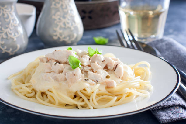 istock Spaghetti with chicken and cheese sauce on a white plate, horizontal 1188577802